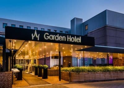 The front view of the Bilderberg Garden Hotel in Amsterdam, showcasing a modern building with a well-lit entrance and a "Garden Hotel" sign.