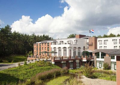 Panoramablick auf das Bilderberg Residence Groot Heideborgh Hotel, umgeben von der natürlichen Schönheit der Veluwe, mit einer modernen Architektur und einem gut gepflegten Garten.