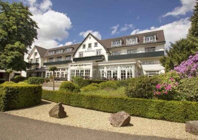 Außenansicht des Hotel De Bilderberg in Oosterbeek, umgeben von gepflegten Gärten und grünen Bereichen.