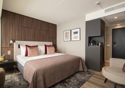 Ein Hotelzimmer im Bilderberg Europa Hotel mit einem komfortablen Bett, sanfter Beleuchtung und einem gemütlichen Sitzbereich.