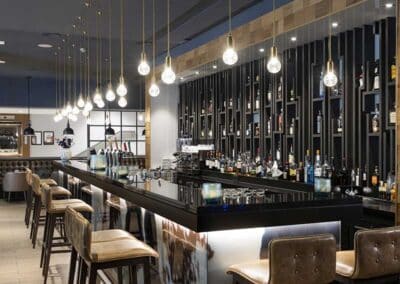 The stylish bar at the Bilderberg Garden Hotel in Amsterdam, featuring modern decor with hanging lights and a well-stocked liquor shelf.