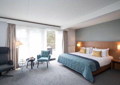 Elegante Suite im Bilderberg Residence Groot Heideborgh Hotel, ausgestattet mit komfortablen Möbeln, einem großen Bett und einem modernen Arbeitsbereich für Geschäftsreisende und Urlauber.