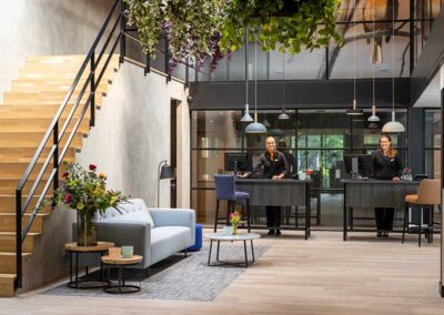 Lobby des Bilderberg Hotel 't Speulderbos mit Empfangstresen, bequemen Sitzgelegenheiten und eleganter Einrichtung