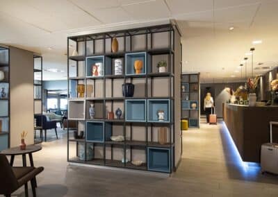 Die geräumige Lobby des Bilderberg Europa Hotels mit modernen Regalen und einem einladenden Empfangsbereich.