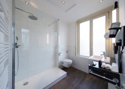 Ein modernes Badezimmer im Bilderberg Grand Hotel Wientjes in Zwolle, ausgestattet mit einer Dusche, Waschbecken und stilvollen Armaturen.