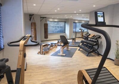 Der Fitnessraum im Bilderberg Europa Hotel mit modernen Trainingsgeräten wie Fahrrädern, Hanteln und Rudergeräten.