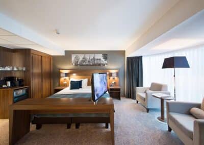 Ein Executive-Zimmer im Bilderberg Garden Hotel in Amsterdam, mit einem großen Bett, einem Schreibtisch, bequemen Sitzgelegenheiten und einem gehobenen Design.